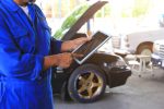 Car mechanic holding digital tablet in auto repair service.